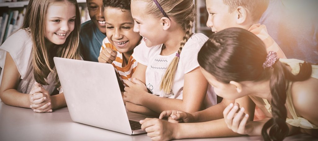 School kids using laptop in library